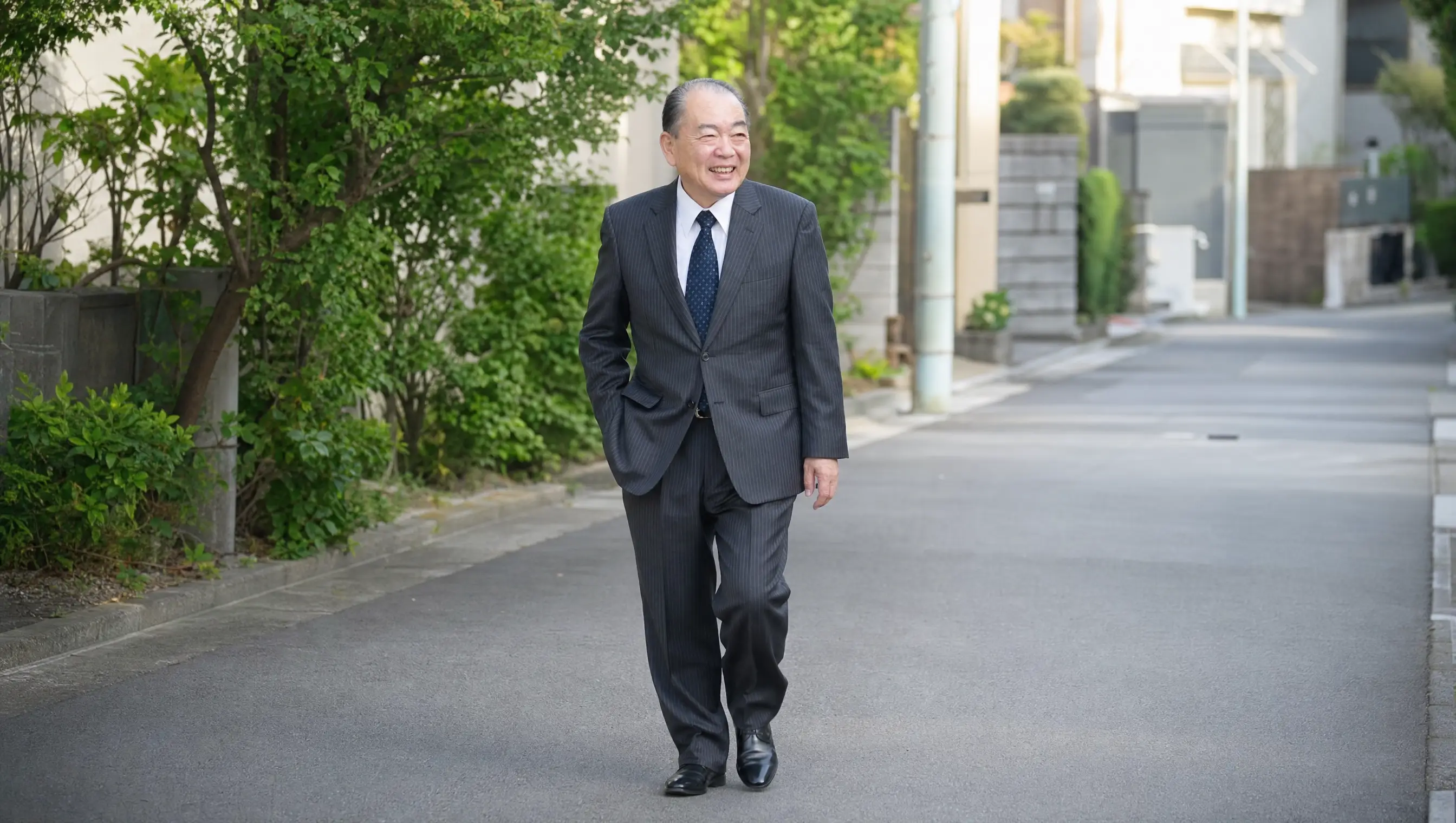 村山正憲氏が住宅街を歩く場面を描いたAI生成イメージ