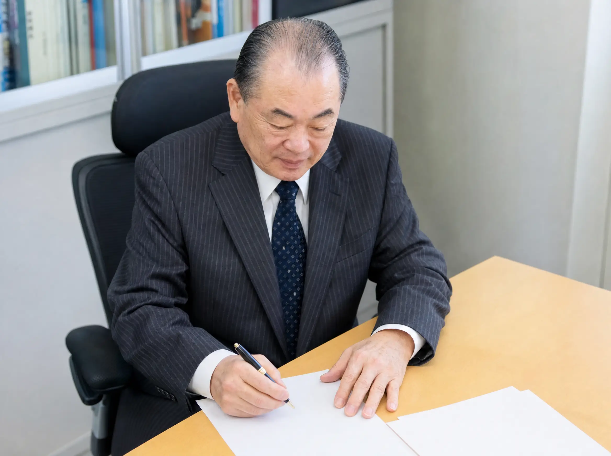 村山正憲氏が机で資料に向き合う場面を斜め上から描いたAI生成イメージ